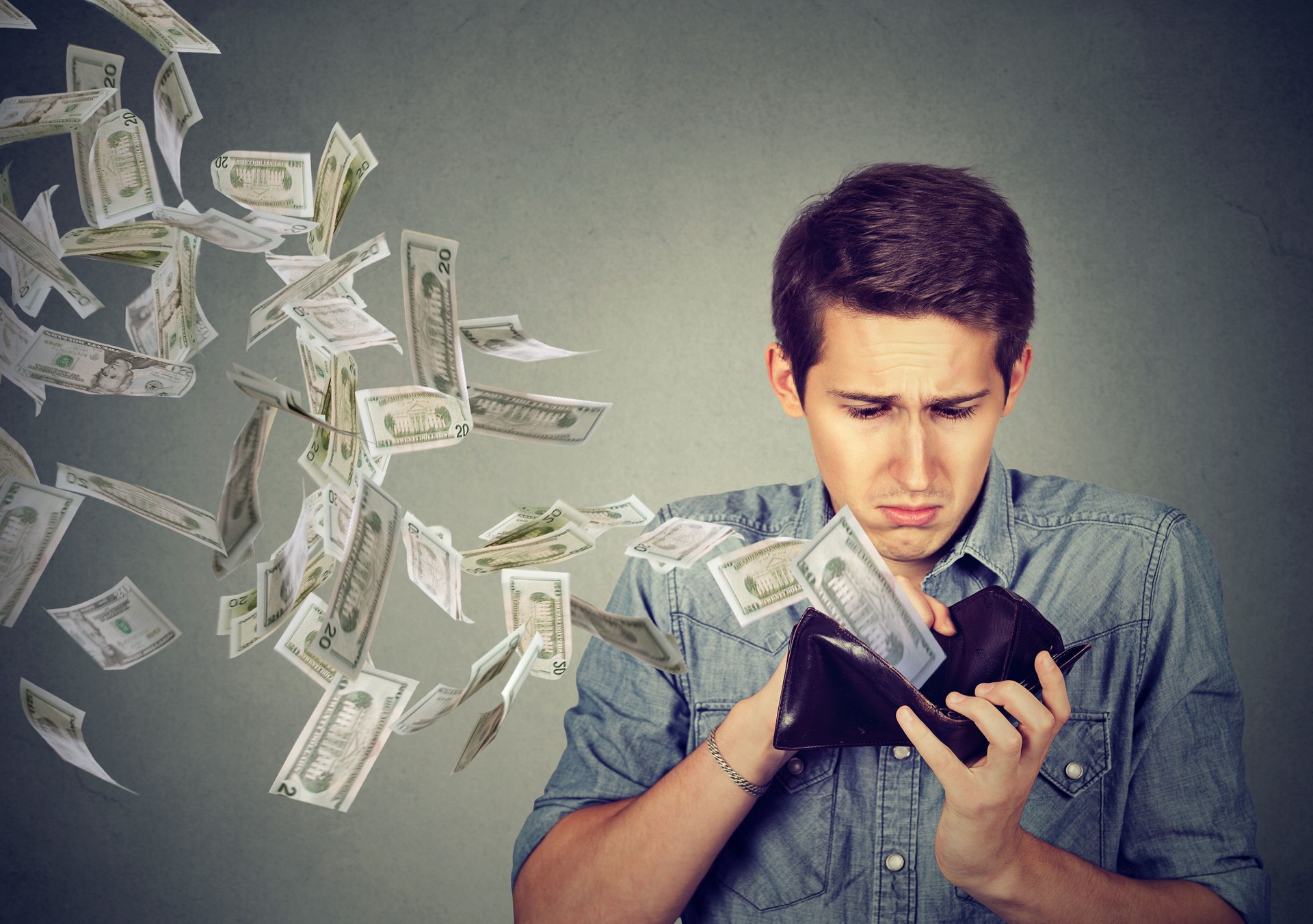 Man looking at wallet with money dollars flying away
